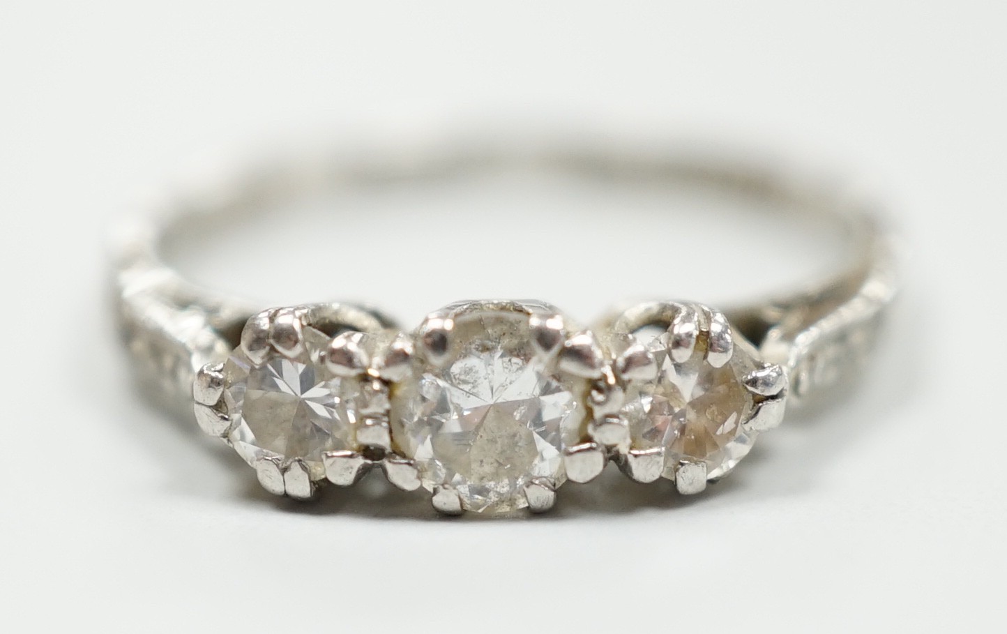 A white metal, stamped plat and three stone diamond set ring, size M/N, gross weight 2.8 grams, with diamond chip set shoulders.